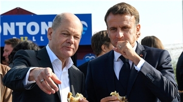 Bundeskanzler Olaf Scholz (SPD) und Frankreichs Präsident Emmanuel Macron (r) essen an der Elbe in Hamburg-Blankenese Fischbrötchen.