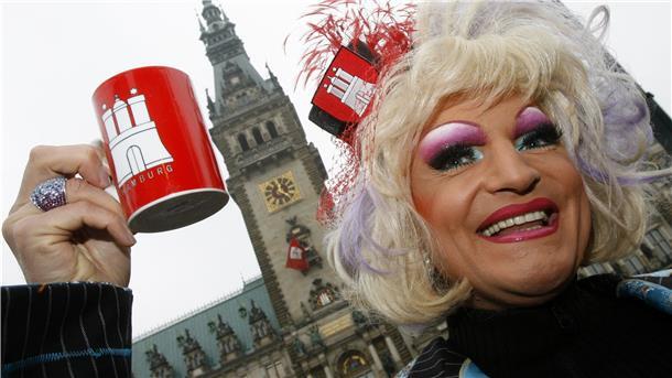 Frau vor Hamburger Rathaus mit Kaffeetasse in der Hand.