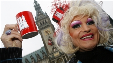 Frau vor Hamburger Rathaus mit Kaffeetasse in der Hand.