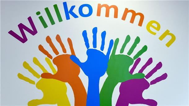 Deutlich mehr Kirchenasyl in Niedersachsen Bunte Hände und das Wort „Willkommen“ ziert eine Wand.