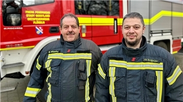 Zwei Feuerwehrmänner stehen vor einem Einsatzfahrzeug der Feuerwehr