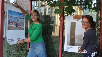 Bushaltestellen werden zum Ausstellungsort. Jane Agena (links) und Doris Becker vom Kunstverein hängen dort Bilder Nordenhamer Fotografinnen und Fotografen auf.