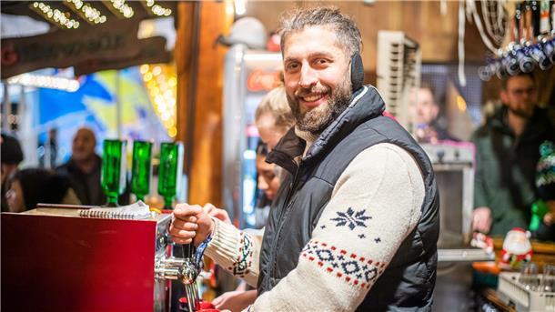 Mann mit Weste zapft Glühwein