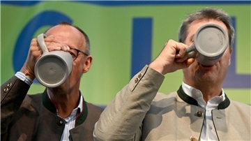 CDU-Chef Friedrich Merz (l) und Bayerns Ministerpräsident Markus Söder (CSU) trinken beim Politischen Frühschoppen Gillamoos auf der Bühne aus Bierkrügen.