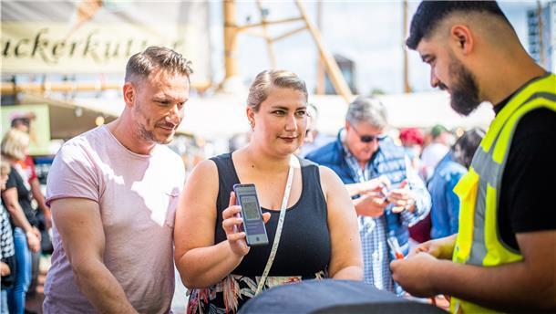 Chantal und Benjamin Kirschmann aus Dortmund zeigen ihren Impfpass vor, um Zugang zum Gelände zu erhalten.