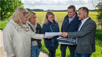 Chiara Bürgerhoff, Lisa Witting, Ricarda Kathen und Lukas Haack (v. li.) gehören zu der Gruppe von jungen Leuten, die in Bramel bauen wollen. IDB-Prokurist Alexander Thorau zeigt ihnen die Pläne des Geländes hinter ihnen.