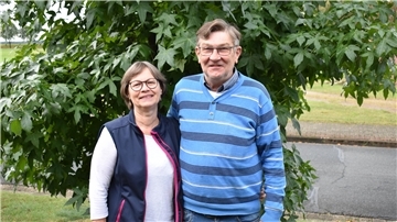 Ein Mann und eine Frau stehen vor einem Baum.