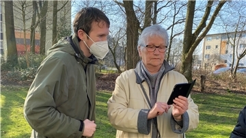 Christian Sanders erklärt Rita Lehm die Funktion ihres Mobiltelefons.