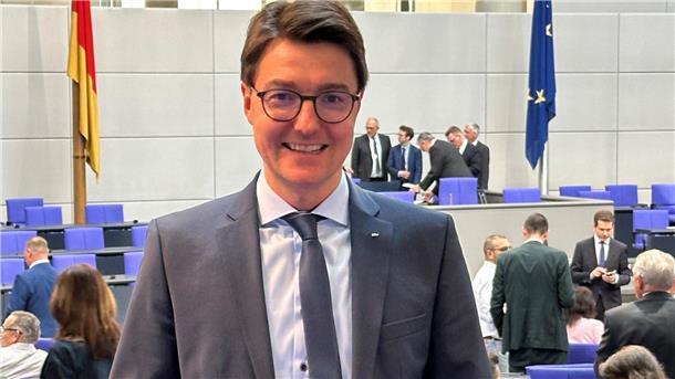 Ein Mann mit Brille und im Anzug steht im Plenarsaal des Bundestages in Berlin.