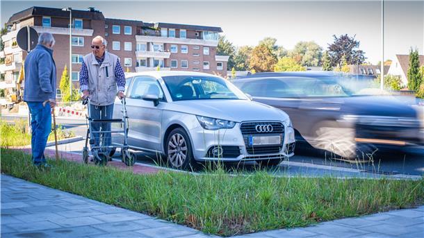 Zwei Männer stehen an der Straße neben geparkten Autos. 