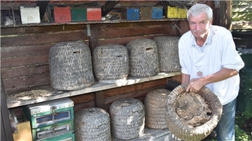 Das Foto zeigt Andreas Bendig mit einem alten Bienenkorb. 