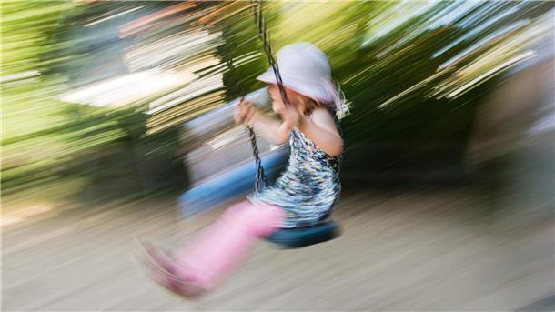 Ein kleines Mädchen schaukelt auf einem Spielplatz