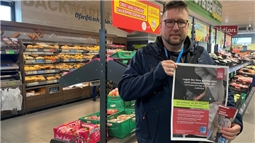 Mann im Supermarkt mit Plakat