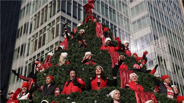 Millionen bejubeln traditionelle Thanksgiving-Parade Darsteller auf dem Macy’s Singing Christmas Tree-Wagen winken den Zuschauern während der Macy’s Thanksgiving Day Parade zu.