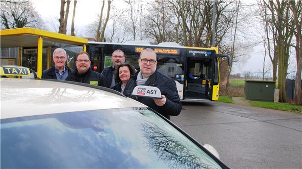 Menschen stehen vor einem Taxi und lachen in die Kamer