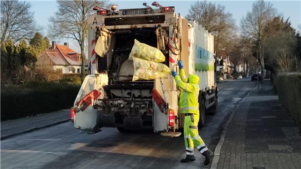 Müllwerker laden Gelbe Säcke auf ihr Fahrzeug.