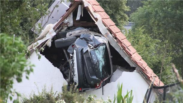 Das Auto liegt nach einem kurzen Flug seitlich in der Mauer einer Scheune.