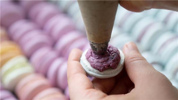 Macarons und Co: Tschüs Nachtisch, Hallo Luxusdessert Das Baisergebäck Macaron wird in einer Bäckerei mit einer Spritztüte befüllt. (Archivbild)