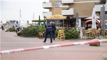 Das Bild zeigt das von der Polizei abgesperrte Umfeld des Tatorts: Mit einem Suchhund fahnden Beamte am Vormittag nach der Auseinandersetzung nach der Tatwaffe.
