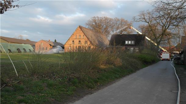 Das Bild zeigt die Einsatzstelle mit dem Bauernhaus in der Mitte, welches von zwei Seiten durch Wassereinsatz gelöscht wird. Rechts unter anderem über das Wenderohr der Drehleiter.
