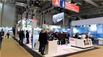 Menschenmenge auf einem Messestand. An der Decke hängt ein großes Schild mit der Aufschrift "Bremen. Bremerhaven. Home of Innovation"
