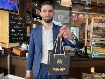 Mann im Anzug mit Tüte in der Hand in einem Laden für Gebäck