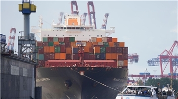 Das Containerschiff „Prague Express“ der Reederei Hapag-Lloyd wird von Schleppern an einen Containerterminal im Hafen gezogen.