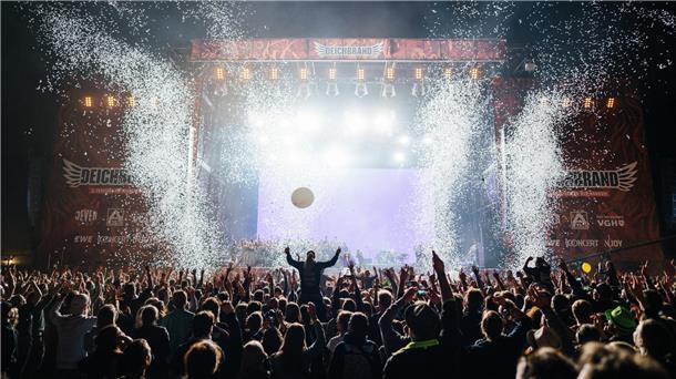 Tausende Festivalbesucher stehen vor einer Bühne auf dem Deichbrand-Festival und jubeln.