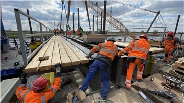 Arbeiter heben ein Brückenelement in die Halterungen