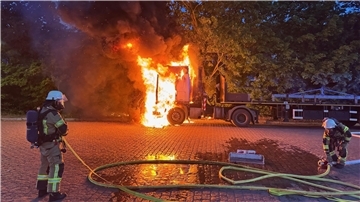 Feuerwehrleute löschen einen brennenden Lkw.