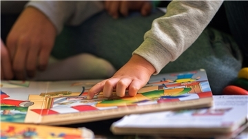Eine Praktikantin liest Kindern während eines Sozialen Tages der Hilfsorganisation Schüler Helfen Leben in einer Kita aus einem Buch vor.