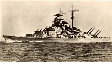 Auf einer Schwarz-Weiß-Fotografie ist ein großes Kriegsschiff zu sehen.