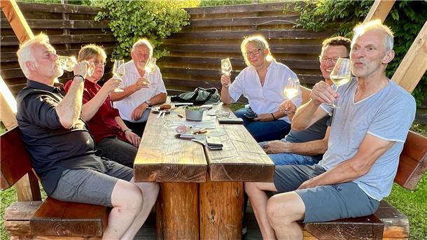 Gruppe an einem Tisch, Wein trinkend.