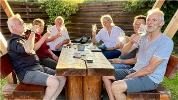 Gruppe an einem Tisch, Wein trinkend.