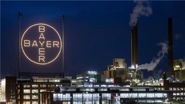 Bayer will ab 2026 zwei Milliarden sparen Das Logo des Unternehmens leuchtet auf dem Werksgelände in Leverkusen.