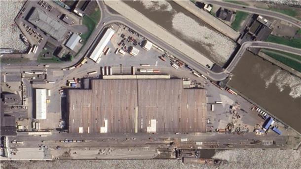 Luftfoto zeigt aus der Vogelperspektive Grundstück mit Lagerhallen direkt im Hafen.