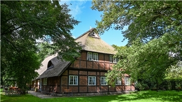 Fachwerkhaus mit weißen Fenstern und Reetdach