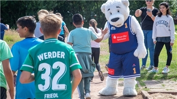 Das Maskottchen der Eisbären Bremerhaven klatscht die Schülerinnen und Schüler ab.