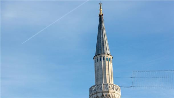 Das Minarett einer Moschee wird von der Sonne angestrahlt.