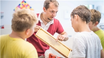 Imker Andreas Bredehorn arbeitet mit Schülern.
