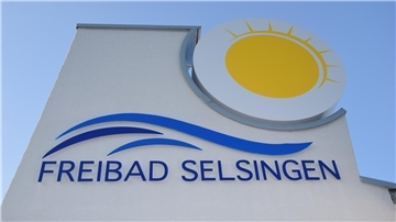 Das neue Logo am Umkleidegebäude des Selsinger Freibades unter blauem Himmel. Noch müssen sich Badefreunde gedulden.