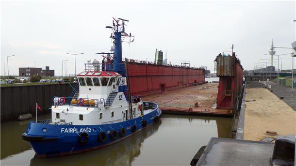 Ein blauer Schlepper und ein rotes Schwimmdock liegen in einer Schleuse
