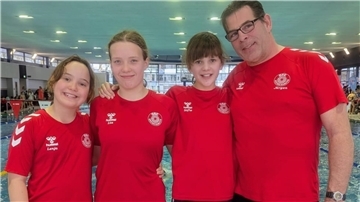 Schwimmerinnen und Trainer vor dem Schwimmbecken.