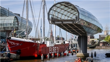 Das sanierte Feuerschiff „Elbe 3" passiert auf seinem Weg von der Bredo-Werft bis zum Liegeplatz im Museumshafen des Deutschen Schifffahrtsmuseums in Bremerhaven auch die Havenwelten, muss durchs Nadelöhr zweier Klappbrücken und der aufgeschwenkten Glasbrücke vorbei am Klimahaus.