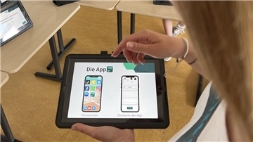 Eine Schülerin zeigt die Ansicht einer App auf einem Tablet