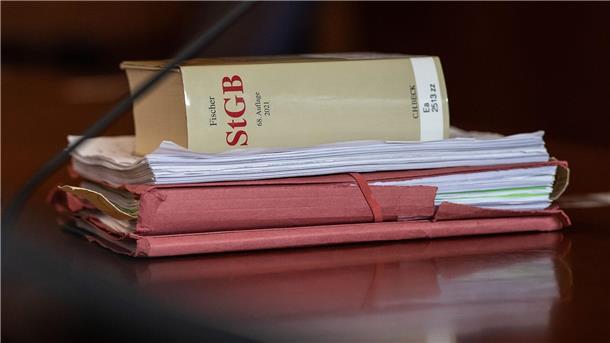 Das Strafgesetzbuch und Akten liegen in einem Gericht auf dem Tisch.