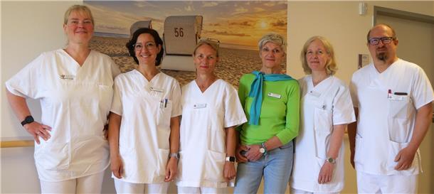 Sechs Mitarbeiter eines Krankenhauses stellen sich zum Gruppenfoto auf. Alle sind in weißer Kleidung zu sehen, bis auf die dritte Person von rechts - die trägt ein grünes Oberteil und eine Jeans. Das Team der Schmerztherapie am Klinikum Bremerhaven-Reinkenheide (KBR) bietet nun stationäre Behandlung auf der neuen Station 2A – mit multiprofessioneller Unterstützung und ganzheitlichem Ansatz.