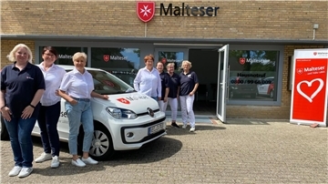 Sieben Personen weißes Auto Gebäude Malteser 