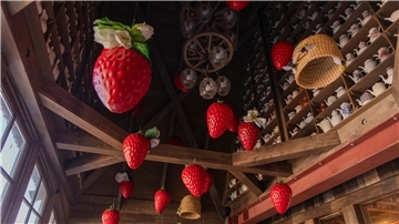 Hohe Holzdecke, die mit künstlichen Erdbeeren und Kaffeekannen dekoriert ist. In Karls Erlebnis-Dorf dreht sich alles um die Erdbeere.