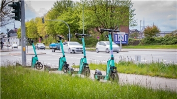Vier E-Roller stehen in einer Reihe an einer vielbefahrenden Straße in Bremerhaven.